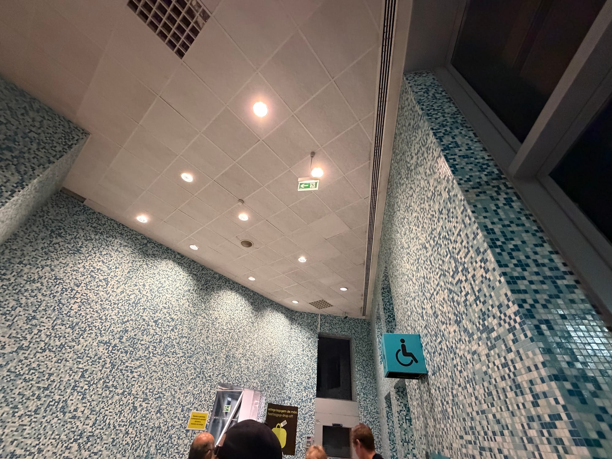 A photo pointing at the celing of an airport gate, with colourful blue moasic tiles on the walls